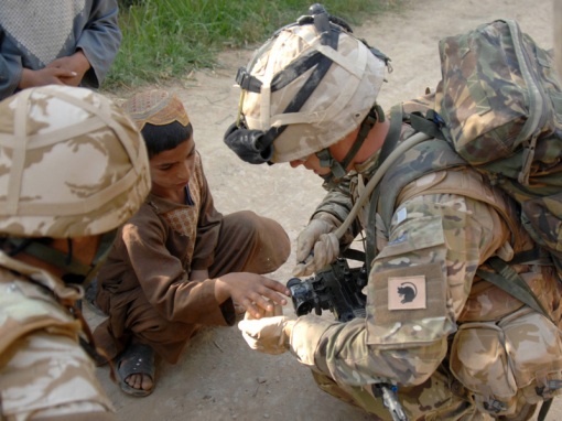 Image shows: Lance Corporal Michael McLoughlin cleaning a cut on a local boy's hand with the water from his camelbak drinking system.  Lance Corporal (LCpl) Michael "Doc" McLoughlin is a medic with the Royal Army Medical Corps attached to The Royal Dragoon Guards. He is currently serving with a ground holding unit on the frontline against the Taliban in the southern district of Nad-e-Ali. The patrol base was seized as part of operation Moshtarak early in the year.    LCpl McLoughlin (22) from Manchester is the first line of medical support for the soldiers of C Squadron Royal Dragoon Guards who are currently operating as an infantry unit for their six-month tour of Afghanistan. The patrol base is some two kilometres from other ISAF locations. It regularly comes under fire from insurgents, as do the soldiers who patrol the surrounding area to provide protection and security for the local villagers.
